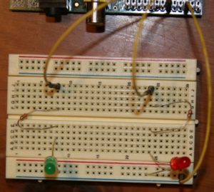 Abbildung 5: Das Breadboard samt LEDs und Verkabelung. Die grüne LED steckt in Reihe 8 und ist mit dem GPIO-Pin 11 über ein Kabel nach J8 verbunden. Die rote LED in Reihe 24 hängt via J24 an Pin 12 des RasPi. Das ganz rechts unten am Breadboard angeschlossene Kabel erdet den Schaltkreis und hängt am GPIO-Pin 6.